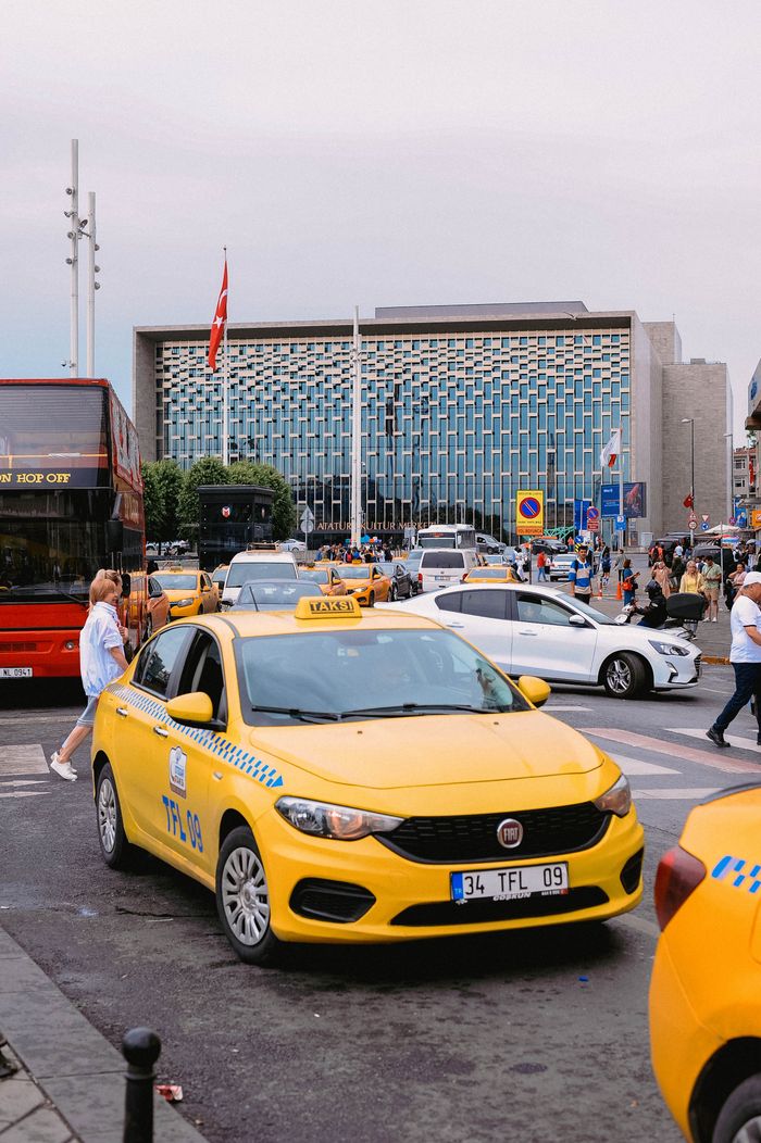 Yellow taxis and bustling street scene in front of a modern building in Istanbul, Turkey.