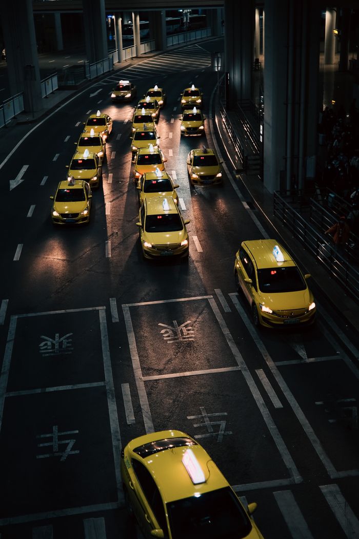 services-03 High angle view of lined yellow taxis on urban street during nighttime.