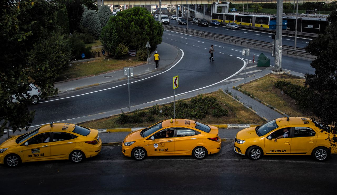 our-experience Aerial view of a city street with three yellow taxis and pedestrians crossing.