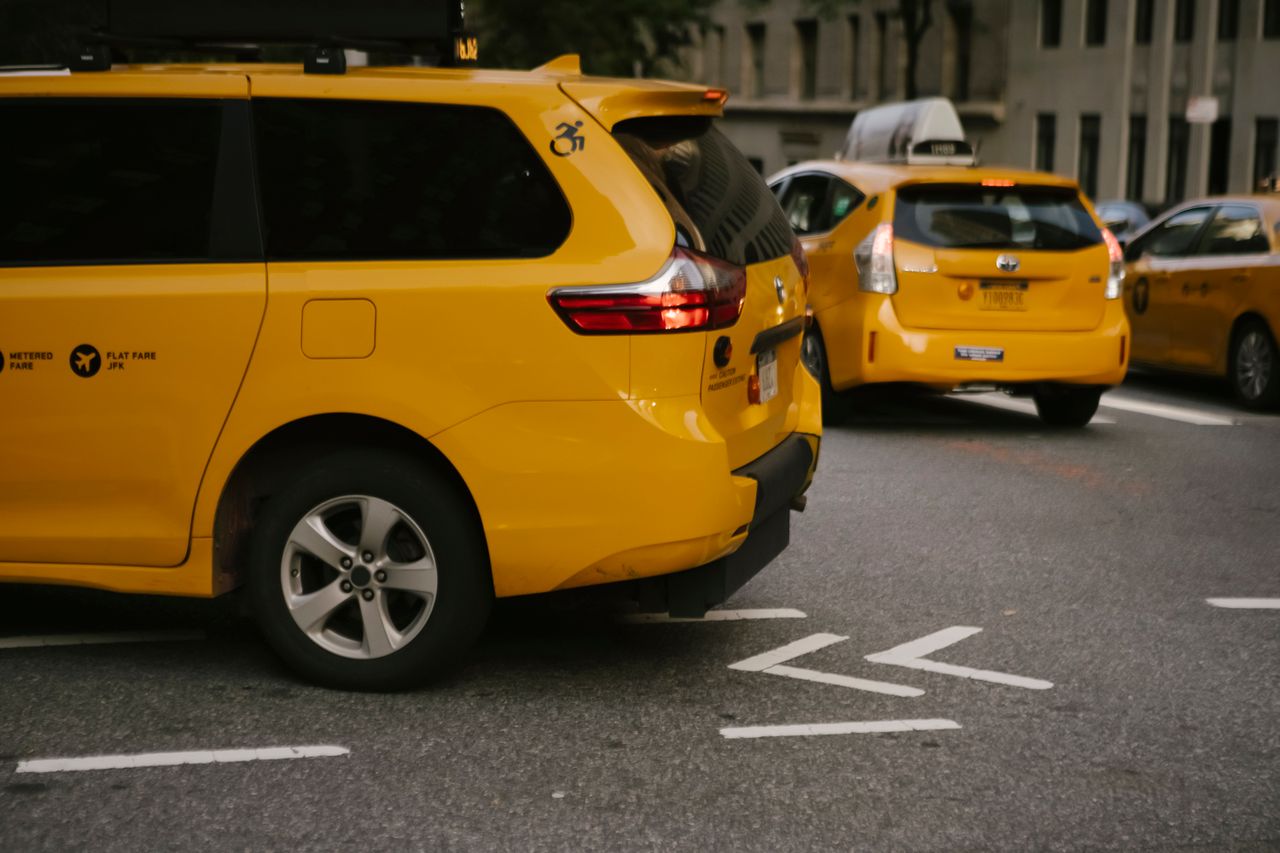 about-02 Modern yellow crossover taxi cars riding on asphalt road near commercial buildings in city
